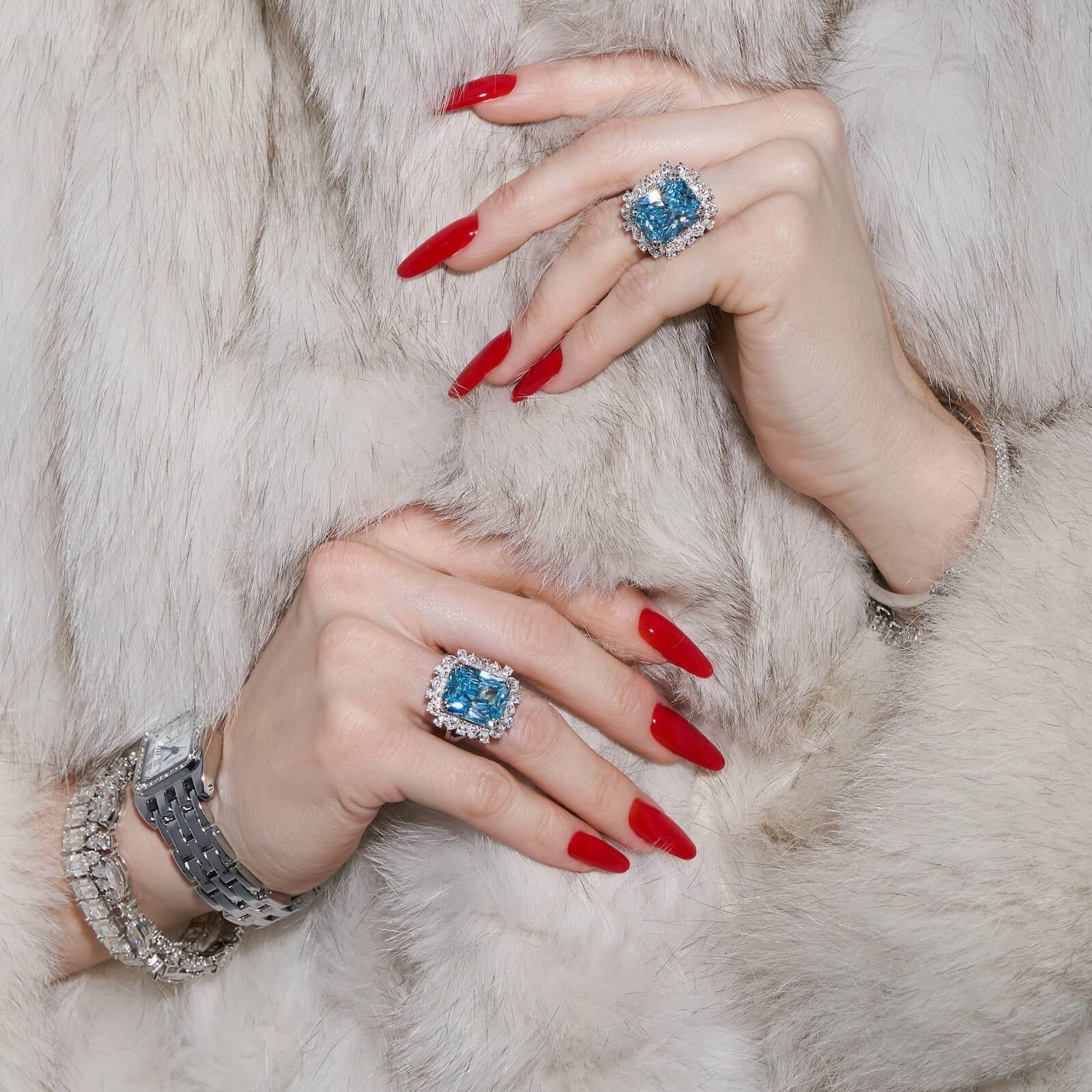 Close-up of model's hands wearing the Sissi statement cocktail ring with a sky blue emerald-cut zirconia center stone and halo cluster in sterling silver