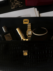 Designer black handbag containing a Cartier watch, the Eternity Moissanite Bangle Bracelet, lipstick and perfume bottle.
