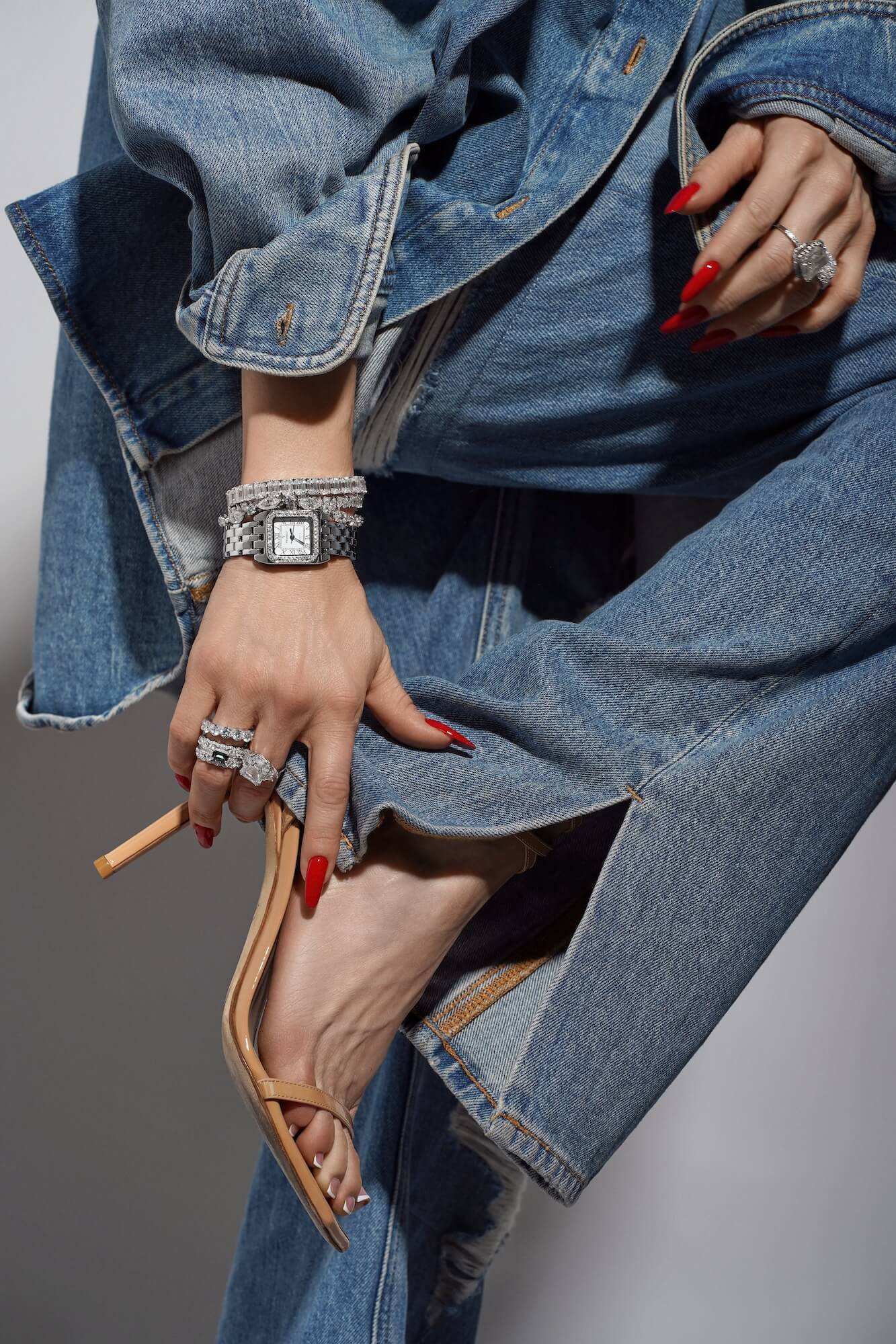Model wearing denim jeans jacket and high-heeled shoes with a variety of Viviana Halil jewelry pieces