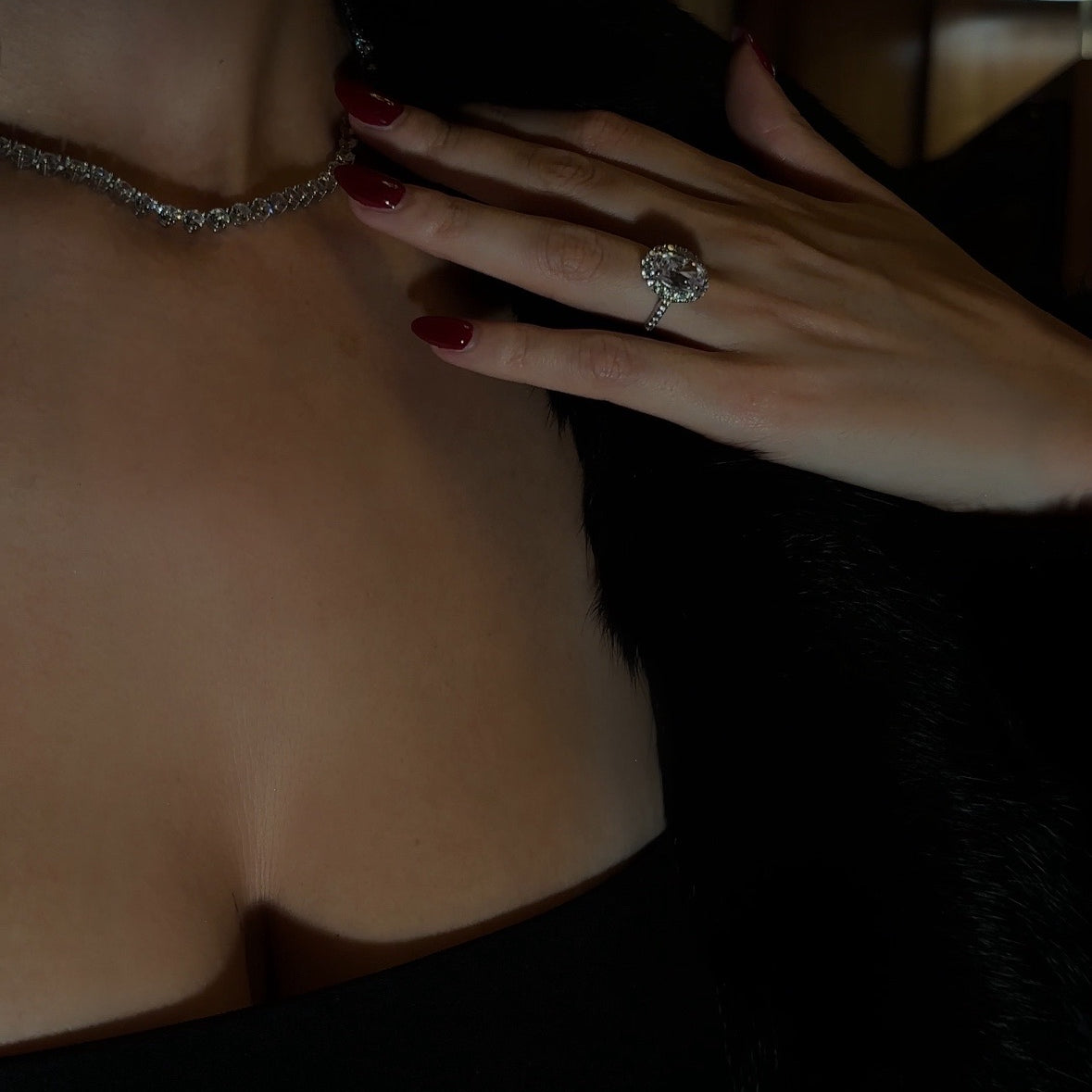 Close-up of a model's hand with the Mon Chéri oval halo ring and the Luxxe Tenné tennis necklace in sterling silver