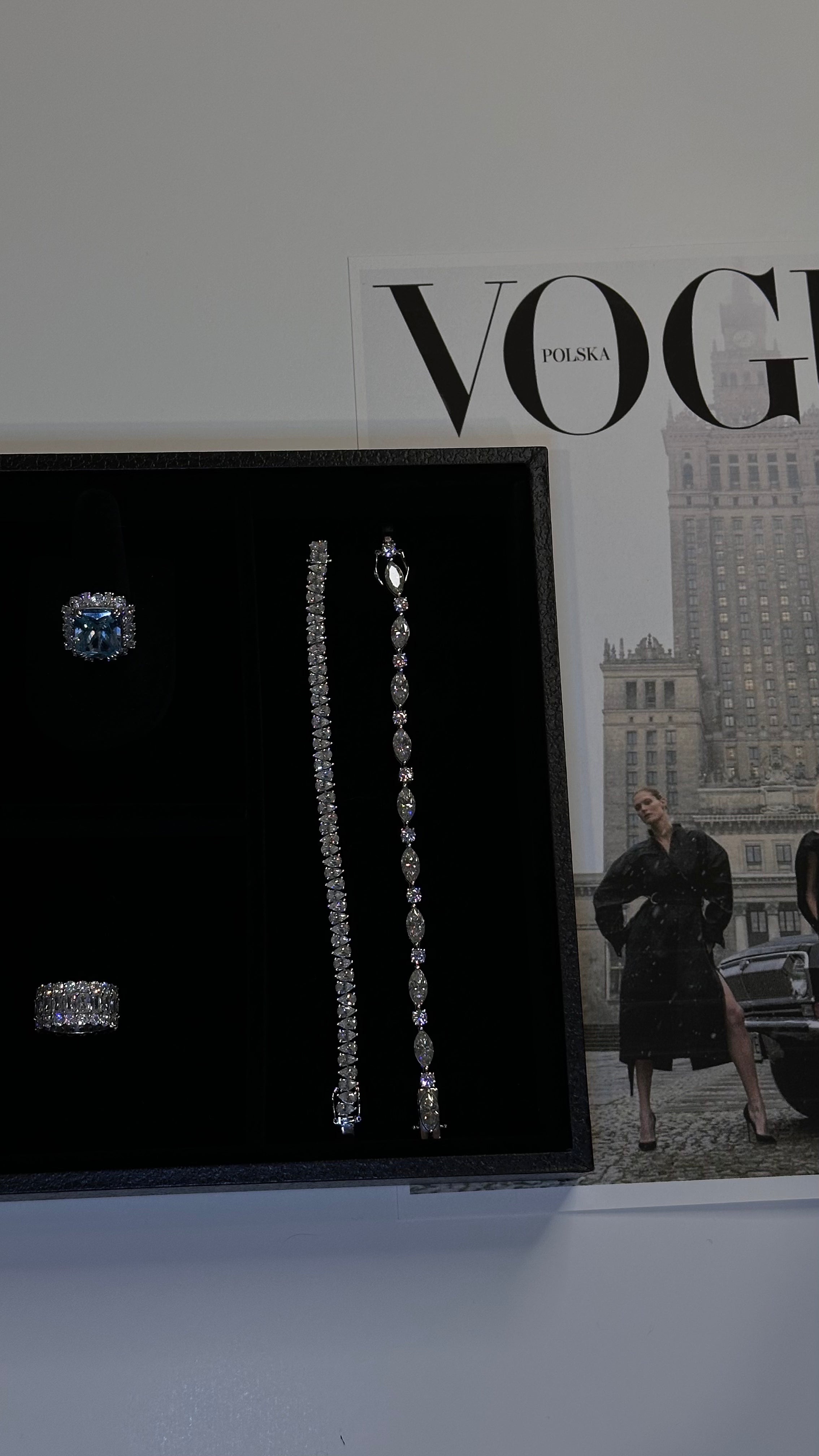 VH earrings are displayed on a black jewelry box along with moissanite tennis bracelets with a Vogue magazine in the background.