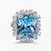 The Sissi Emerald-cut sky blue zirconia cocktail ring with double claw prongs and a mixed halo of round, pear, and marquise-cut stones
