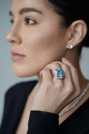 Viv Halil wearing The Sissi Ring by Viviana Halil a large blue sapphire ring with a multi-cut halo design, surrounded by a sterling silver band.