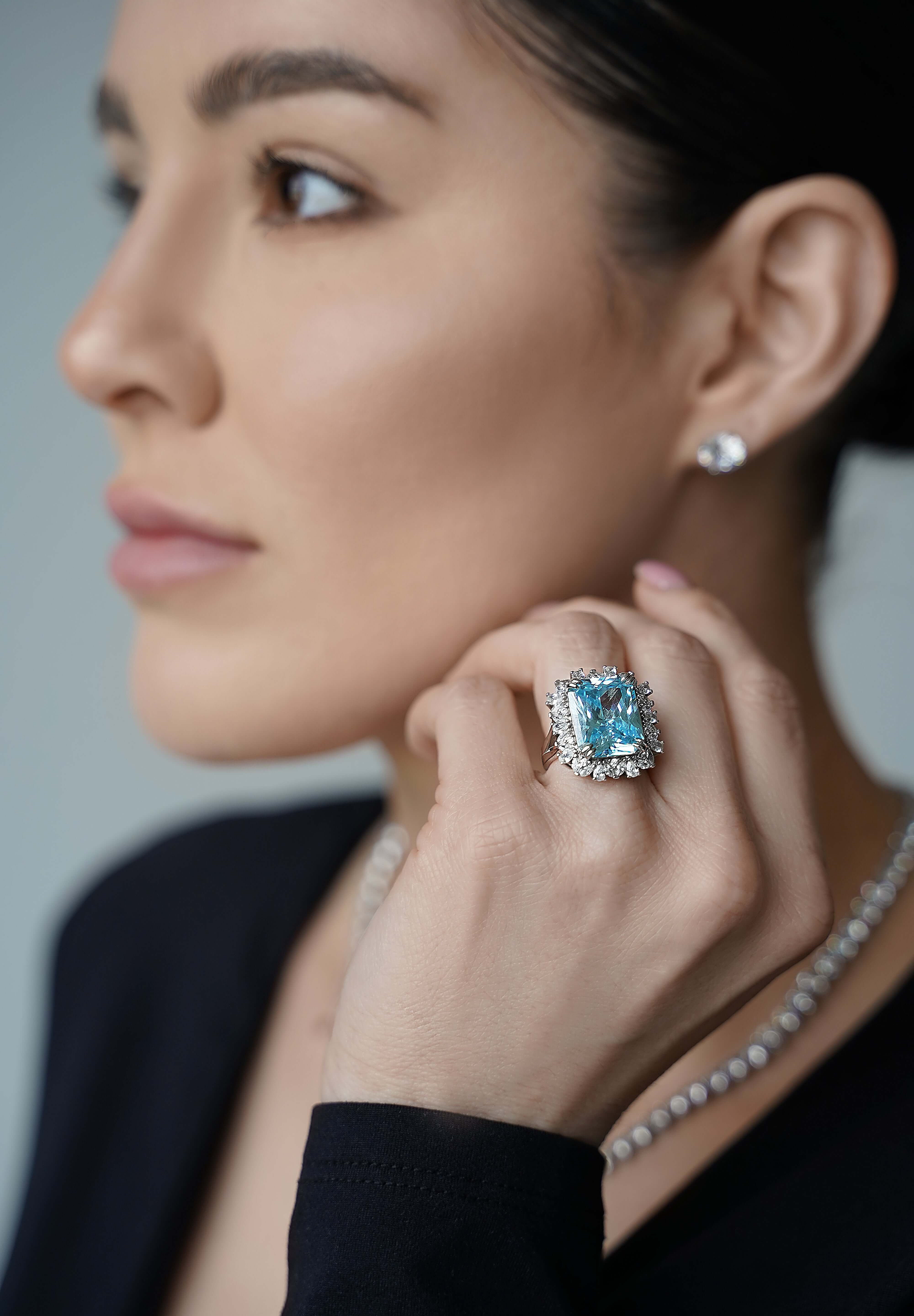 Viv Halil wearing The Sissi Ring by Viviana Halil a large blue sapphire ring with a multi-cut halo design, surrounded by a sterling silver band.