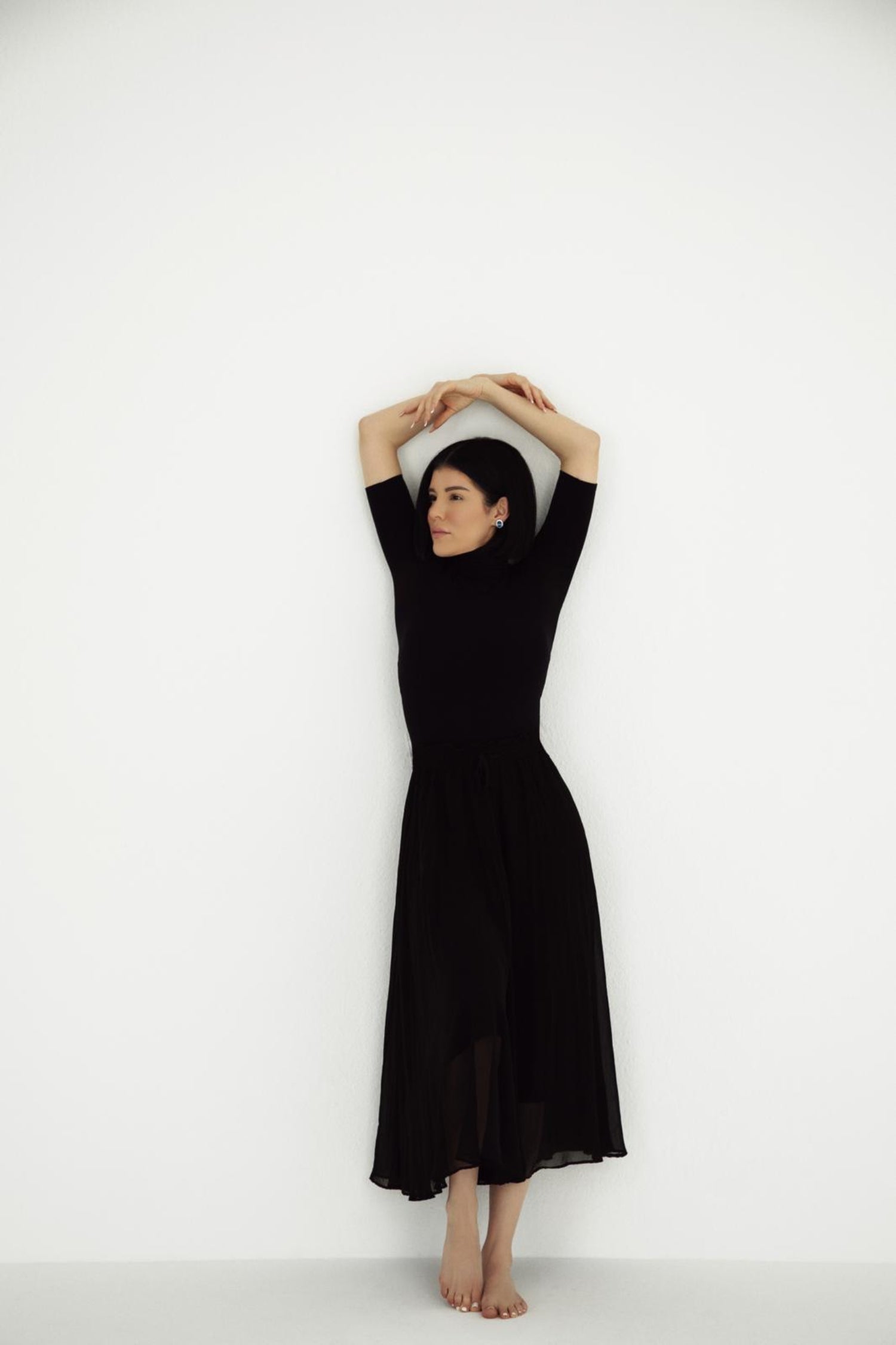 Viv Halil wearing The princess diana earrings a black dress against a white background photo shoot