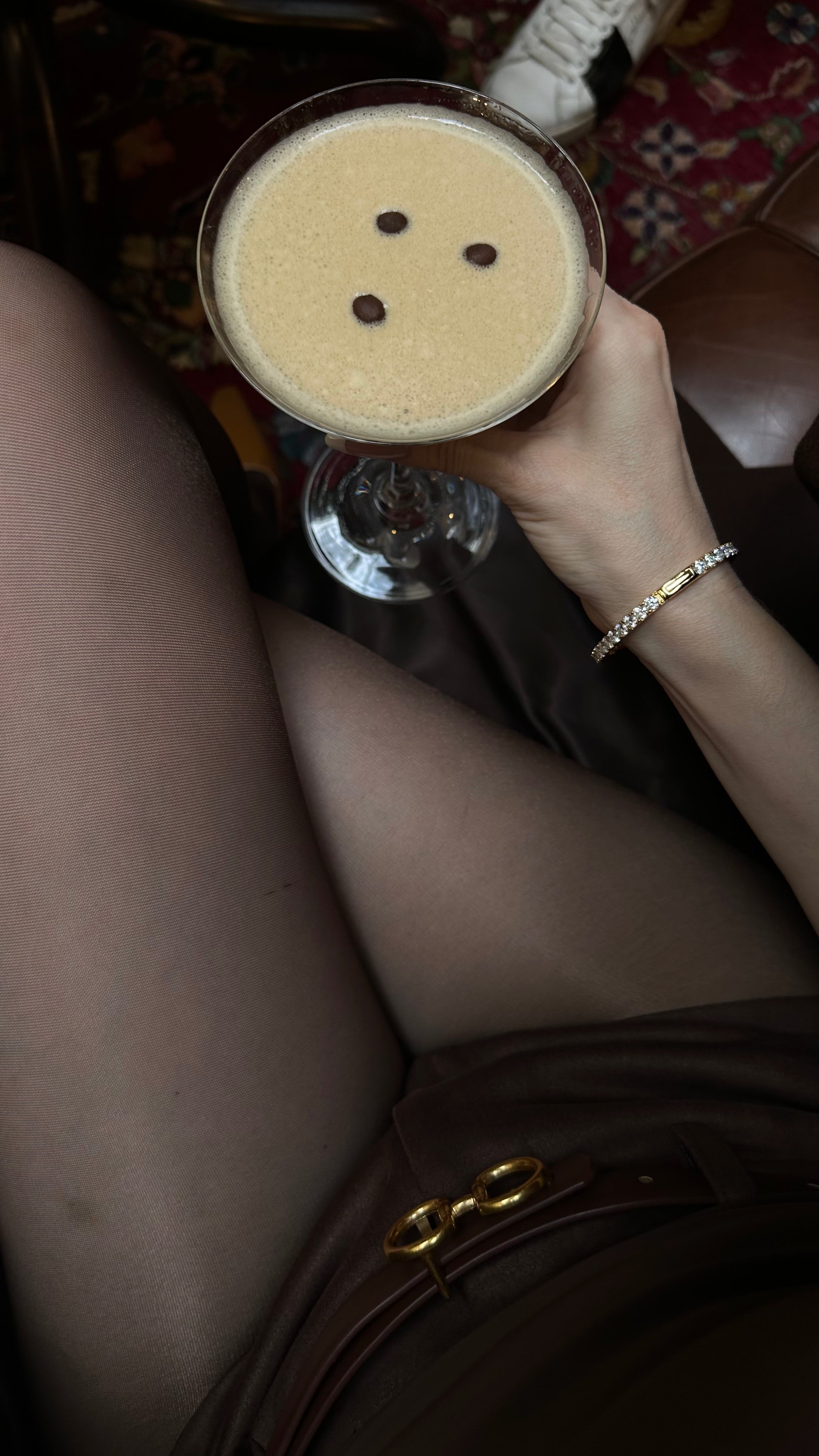 The Eternity Moissanite Bangle Bracelet in 18k gold vermeil, worn by a model Viv halil drinking an espresso martini, luxury jewelry redefined by Viviana Halil Beverly hills. 